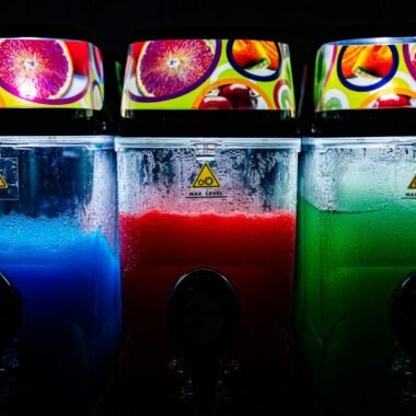 three soda machines with different colors of liquid